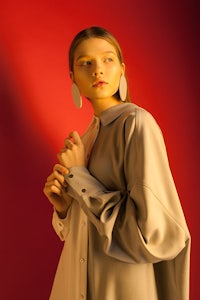 a woman in a grey shirt posing on a red background