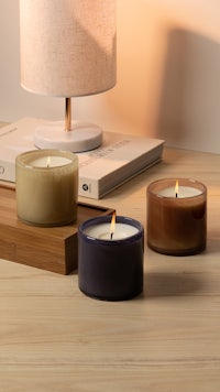 three candles on a wooden table next to a lamp