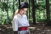 a woman in a black shirt and leopard print skirt is standing in the woods