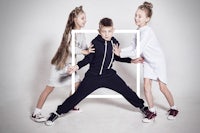 three children posing in front of a white frame