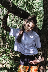 a woman is leaning against a tree